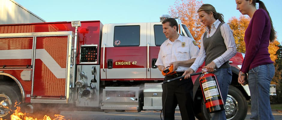 Instructor teaching staff to use a fire extinguisher